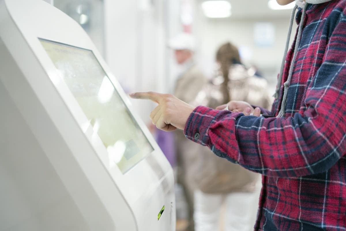 mężczyzna pobierający numerek z automatu